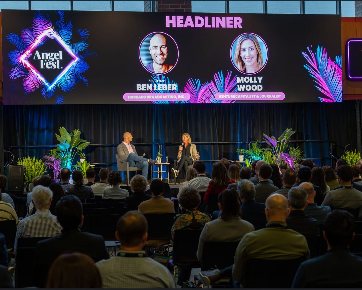 A photo of Molly Wood and Ben Leber in conversation on a stage with an audience in front of them. A banner above them reads HEADLINER and has their names and photos.