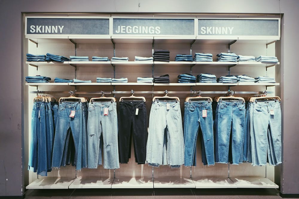 Shelving in a shop containing two fits of jeans in a range of colours. The labels above the shelves say: skinny, jeggings, skinny.