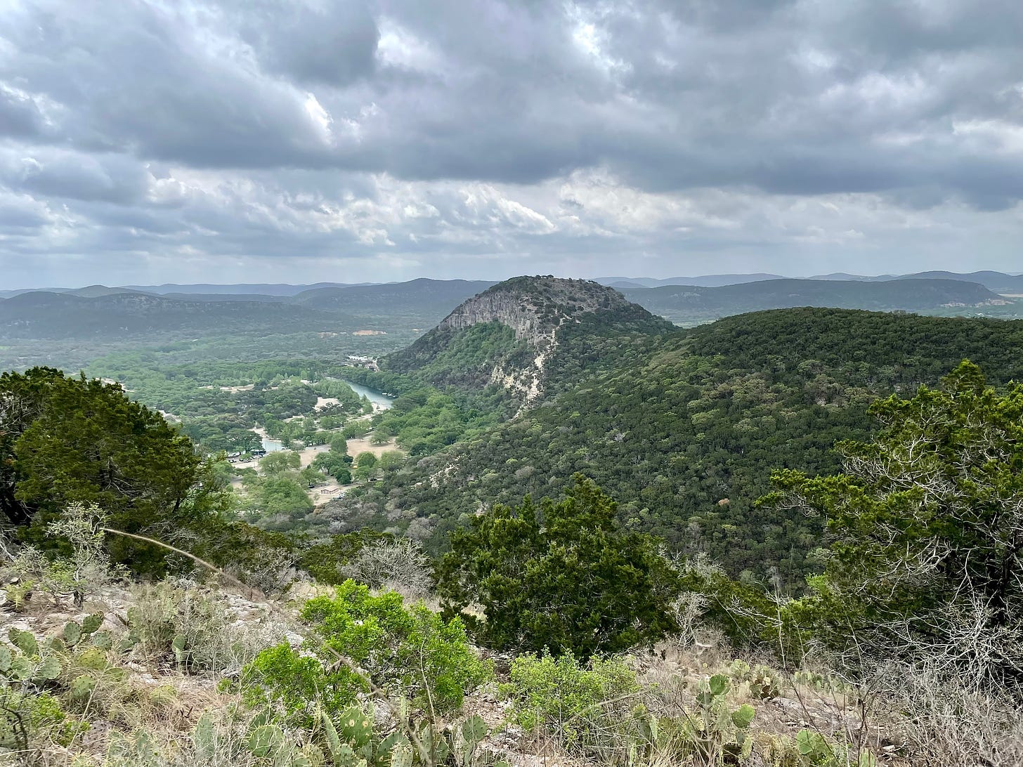 A photo of Old Baldy in Garner State Park with a backdrop of big gray clouds