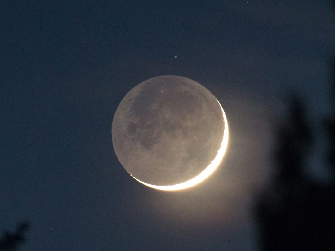 a crescent moon is seen in the night sky