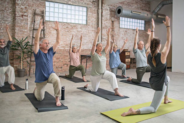 Senior people and coach doing warrior pose in gym Senior people and fitness instructor exercising in warrior position at gym. Active seniors are exercising on exercise mats at health club. They are performing yoga together in studio. kneeling lunge stock pictures, royalty-free photos & images