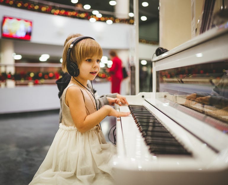 A young girl sits at a pianoto paly a song she just comosed herself.