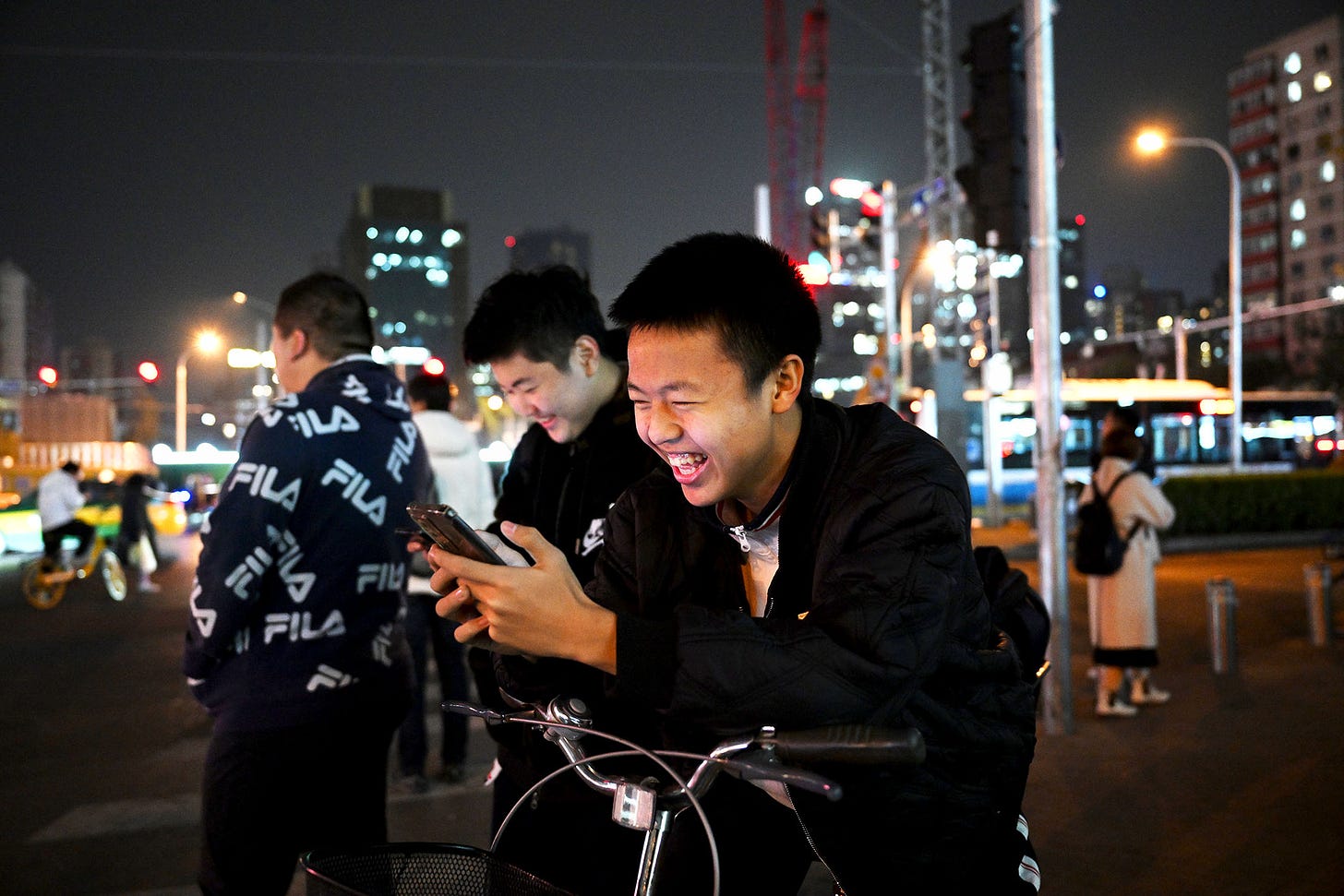 2023年11月15日，中國北京，學生在馬路口等待時玩手機遊戲。攝：Kevin Frayer/Getty Images