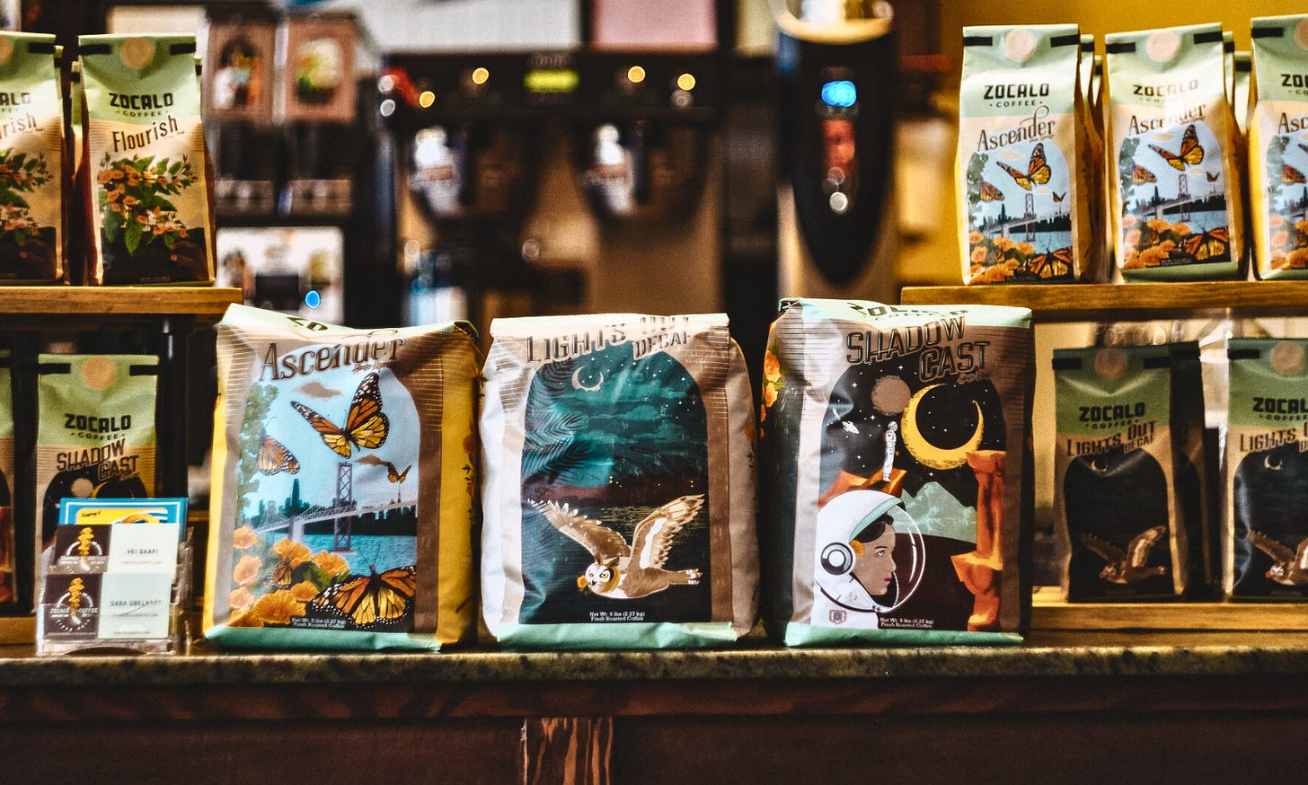 A shelf filled with elaborately illustrated coffee bags featuring illustrated artwork.