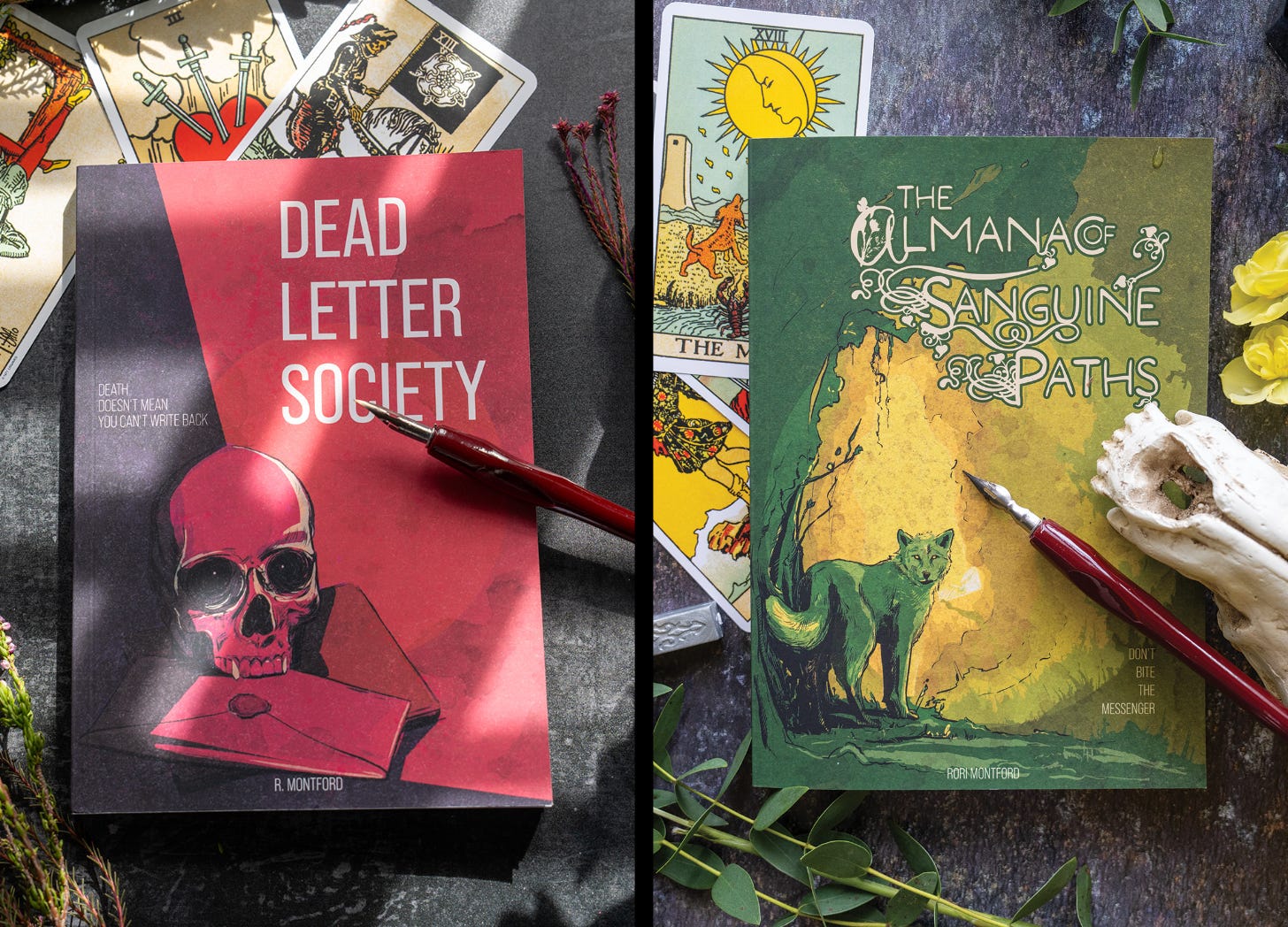 Two books among tarot cards, a fountain pen, and occult paraphernalia. One book’s cover is a deep red with a skull, the other a forest green with a wolf.