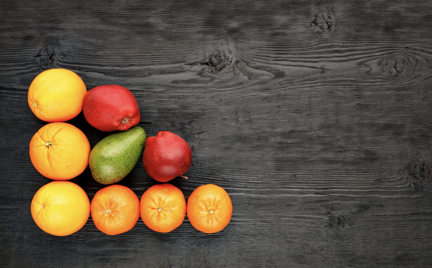 Ripe fruits and citrus fruits lie on an old black wooden table.