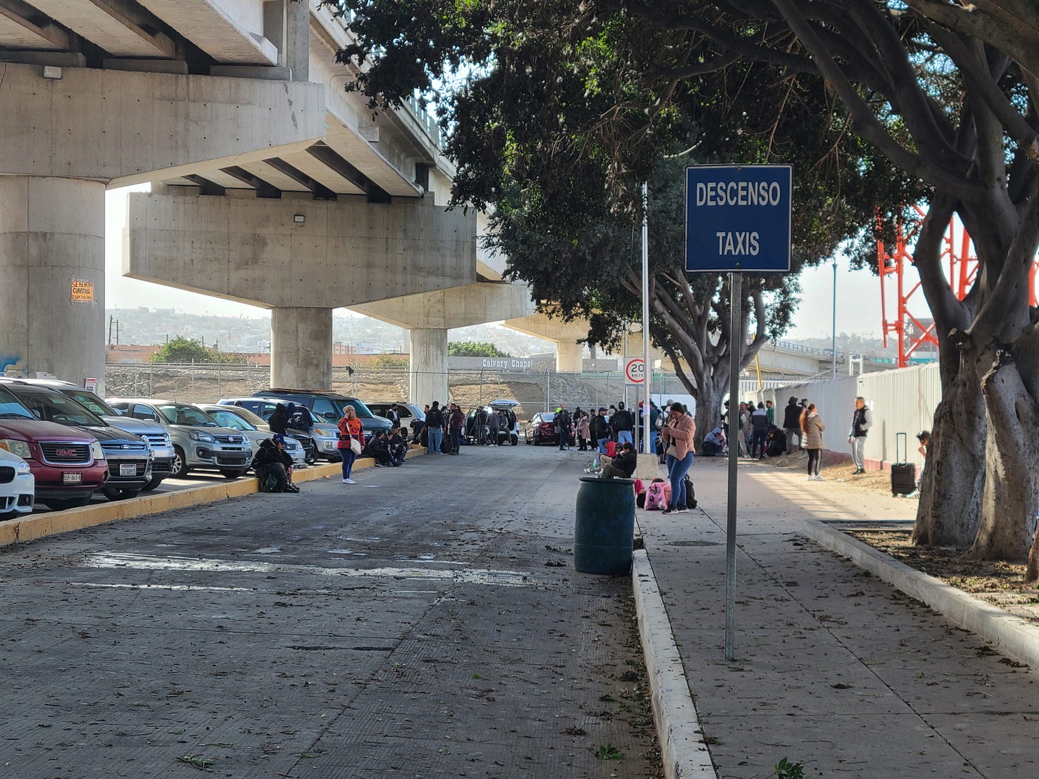 people stand under a bridge next to the port of entry