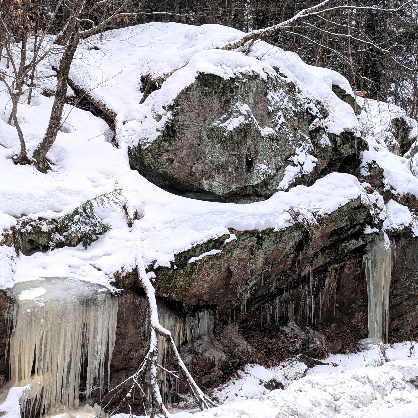 A photo of a mound of Canadian shield rock covered with snow and icicles in Muskoka.
