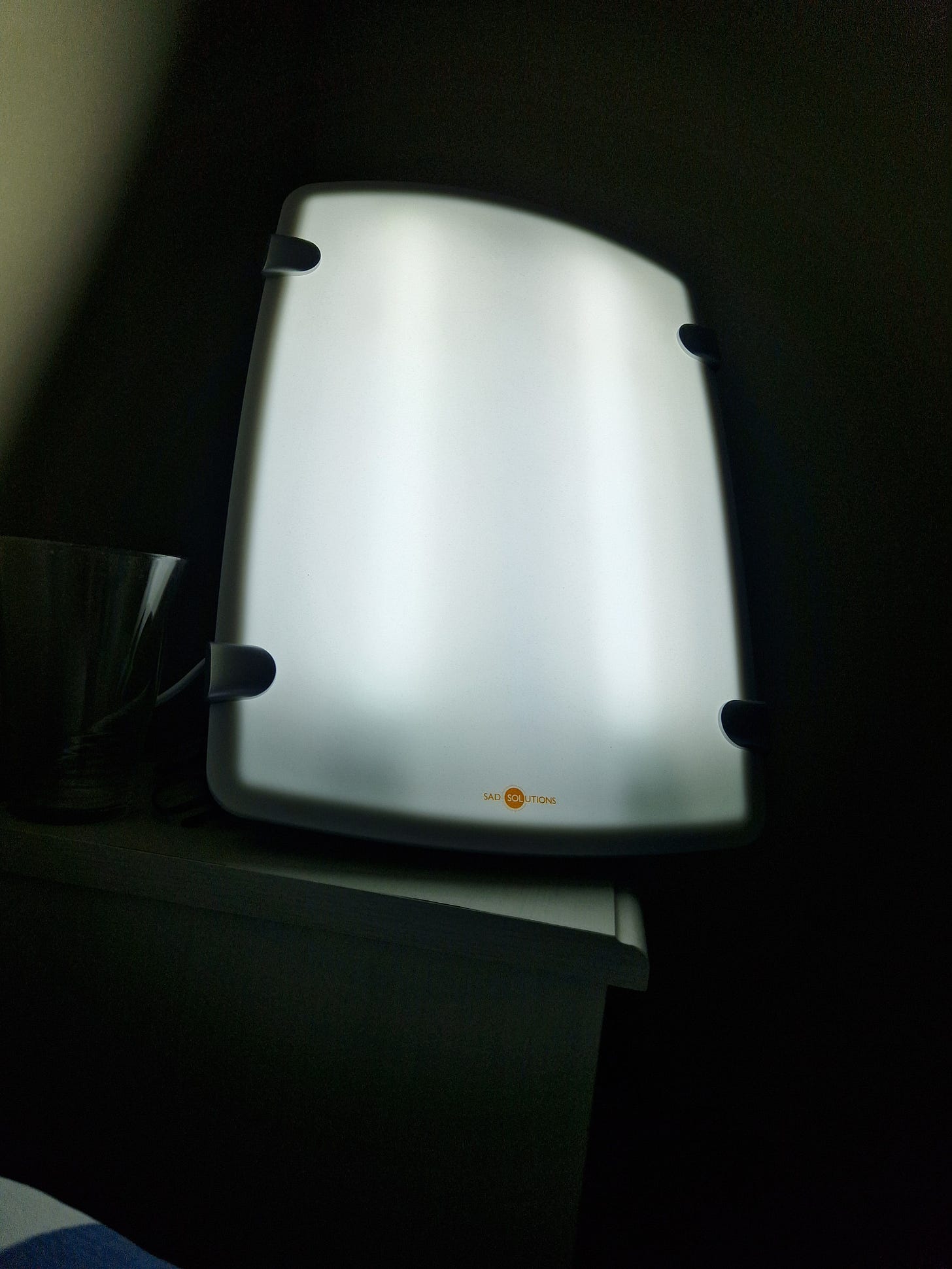 My SAD lamp illuminated on my bedside table. 