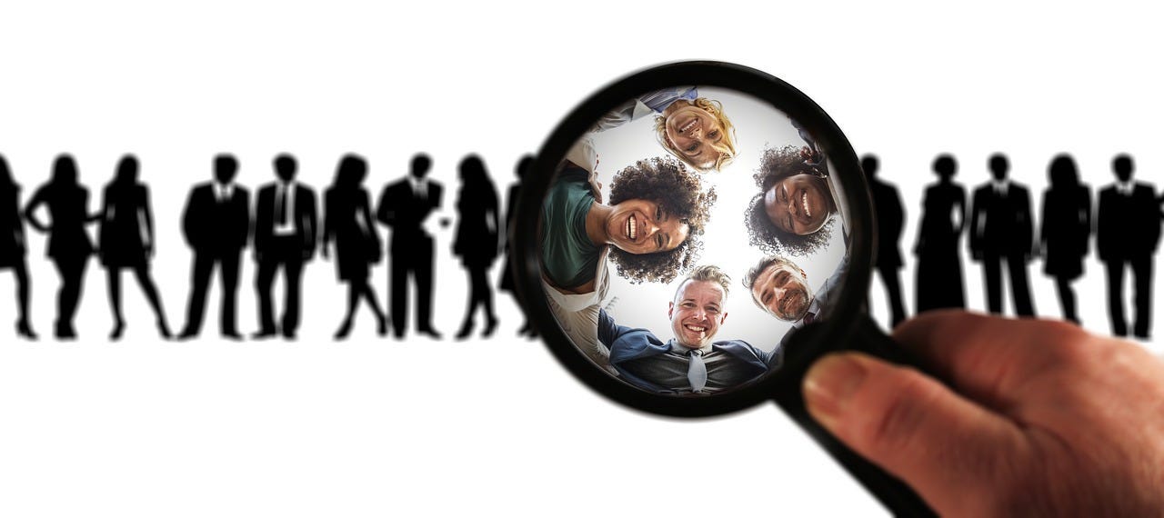 Depiction of using a magnifying glass on a group of readers in order to zoom in on your specific niche audience to make the most impact and deliver the most value.