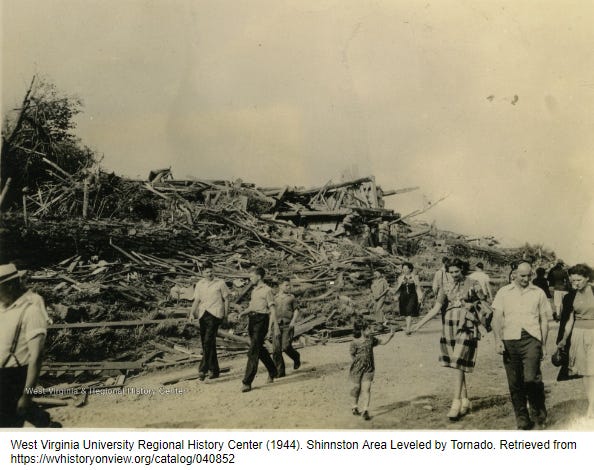 Old photograph showing people of Shinnston, WV walking past a large pile of debris from the tornado that struck their community.