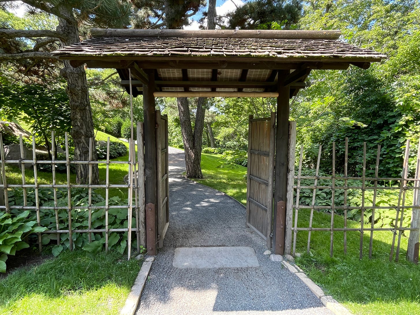 An open bamboo gate under a roof at the entrance to the gardens around a Japanese tea house