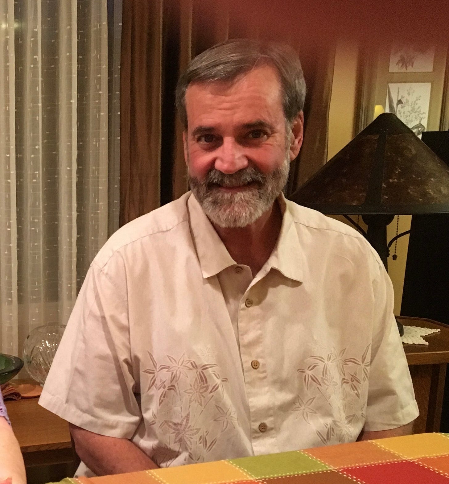 Middle-aged man with a short, graying beard sitting at a table.