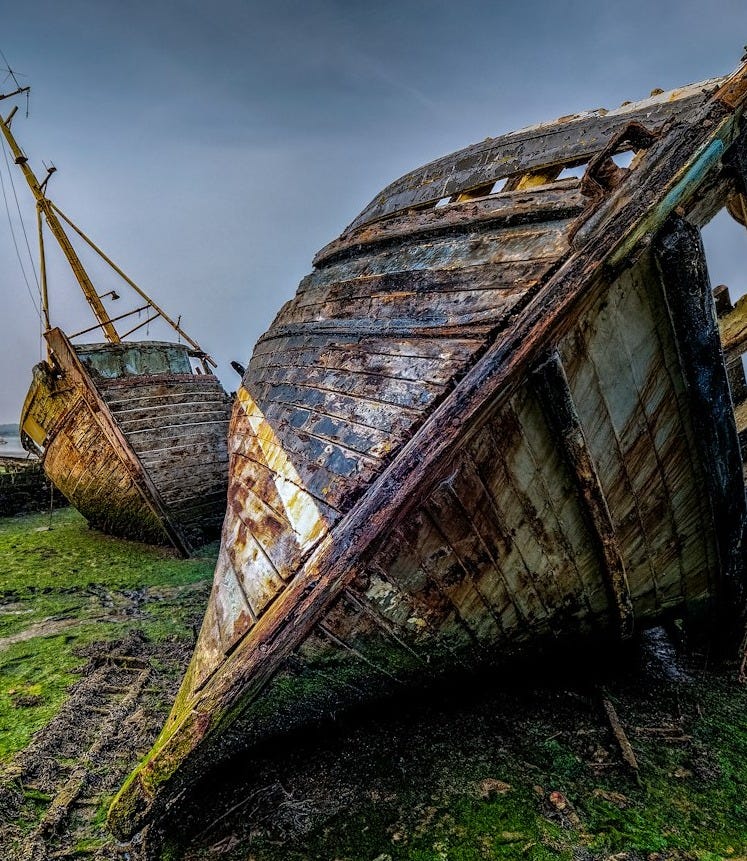 A couple of boats sitting on top of a lush green field