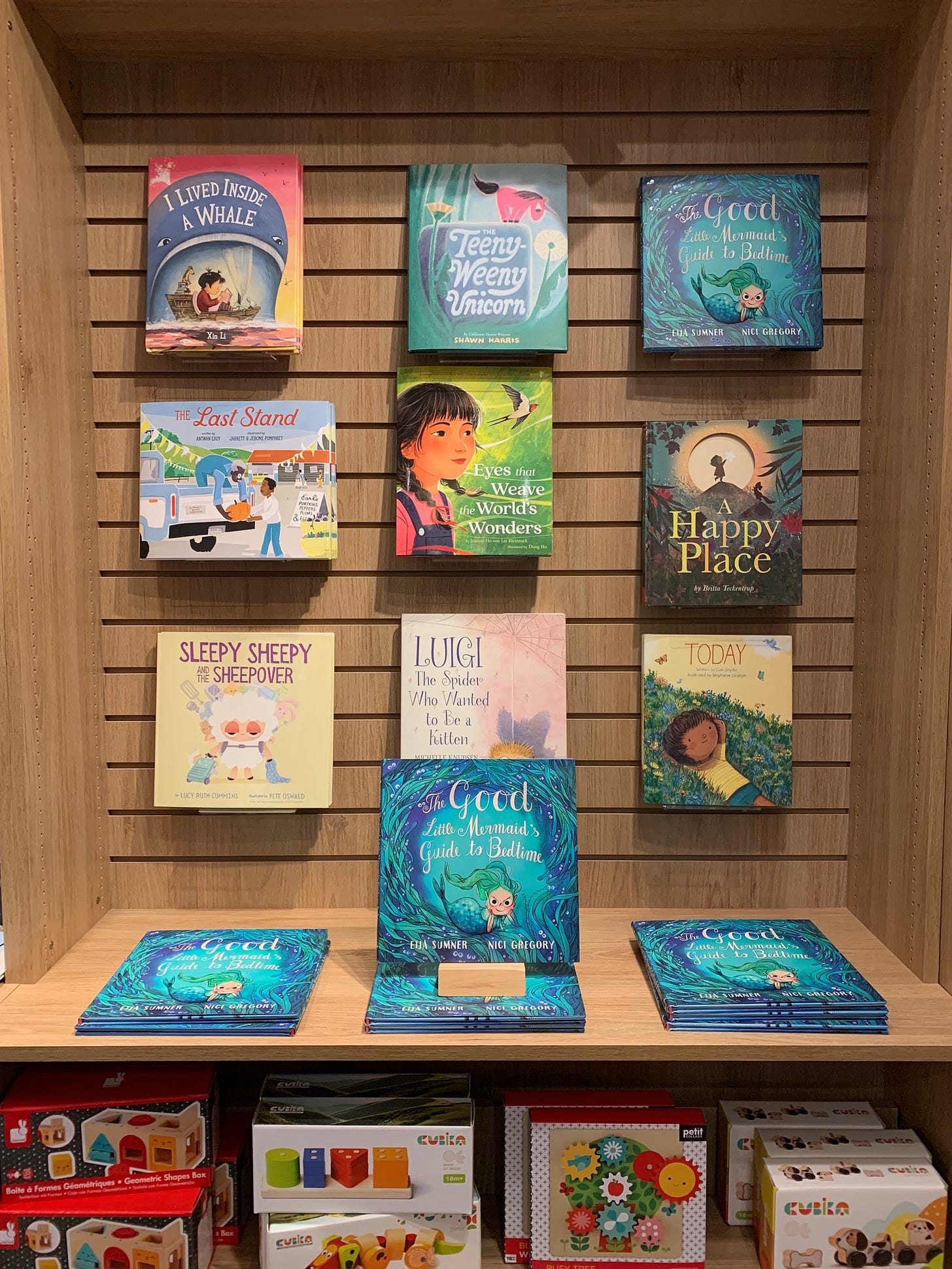 A bookshelf with picture books on display and Eija's book The Good Little Mermaid's Guide to Bedtime prominently featured.