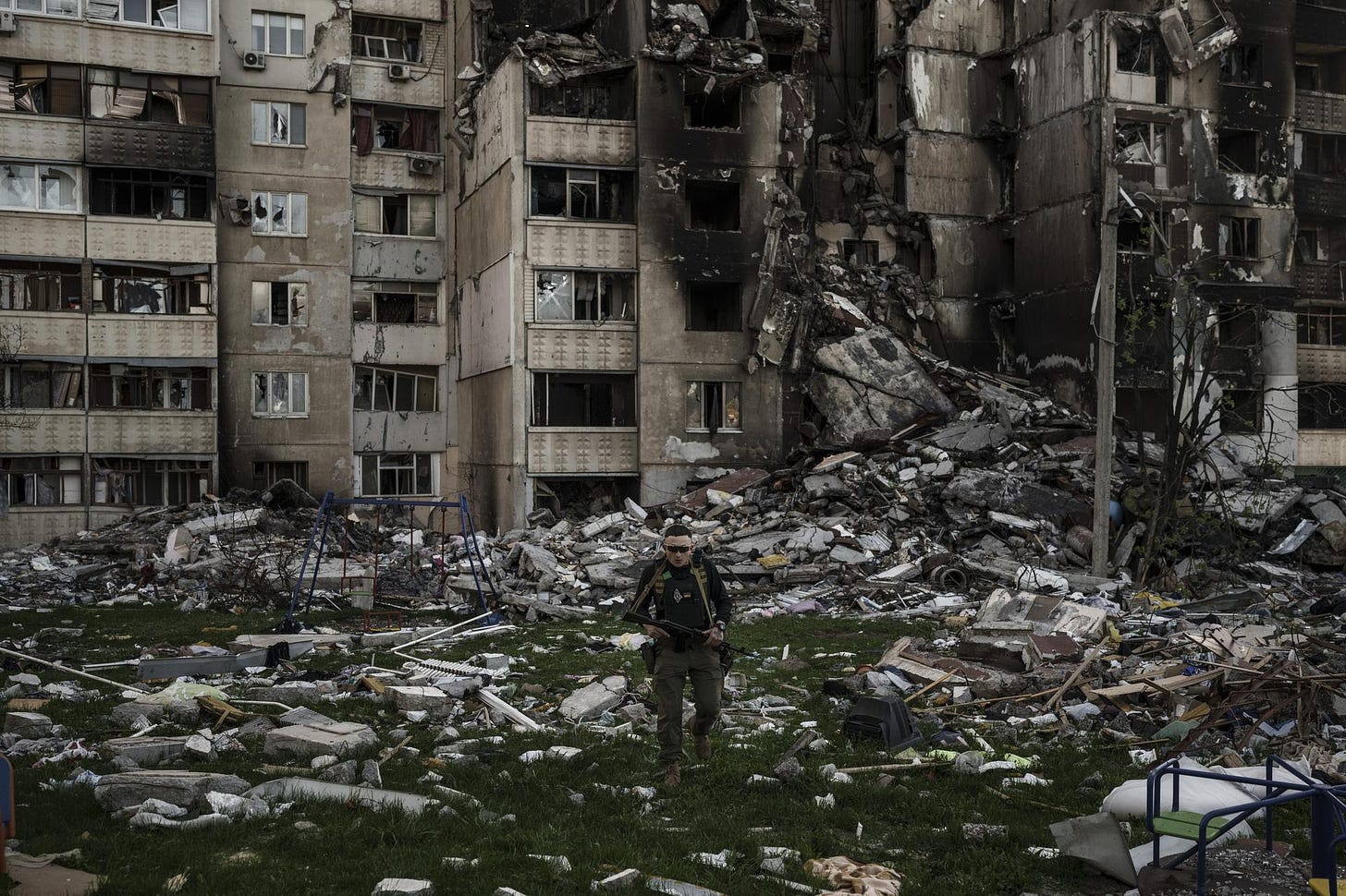 A Ukrainian serviceman walks amid the rubble of a building damaged by Russian bombardment