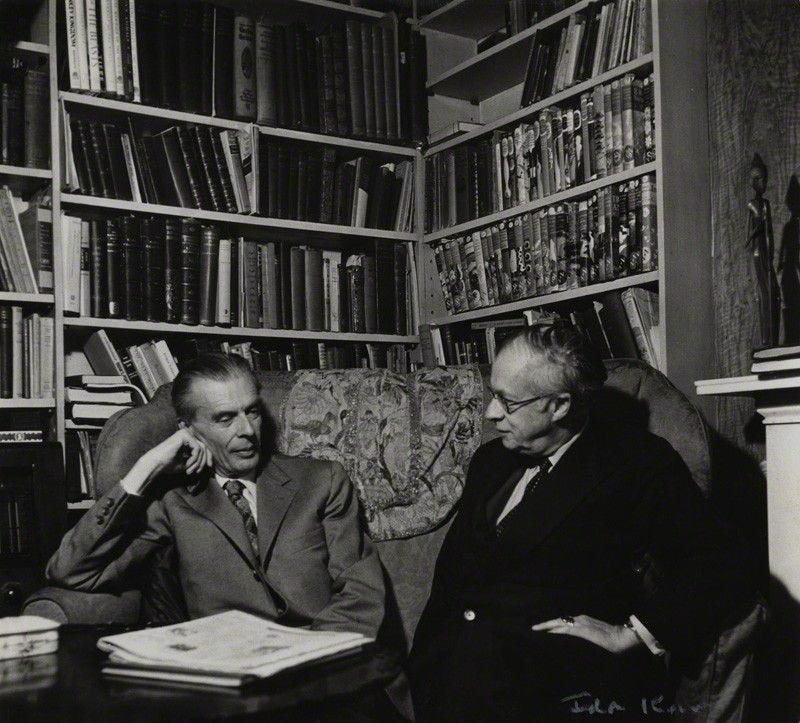 black and white photograph of two men sitting in front of bookshelves