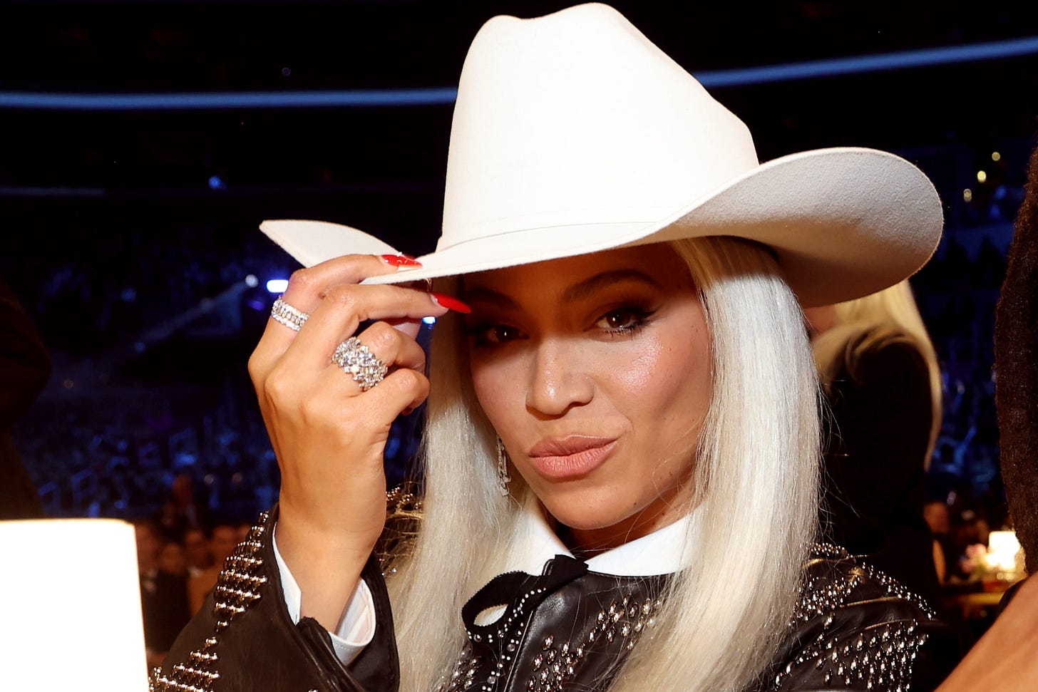 A picture of Beyoncé wearing a cowboy hat and gingerly touching it with her right hand at the 2024 Grammys 