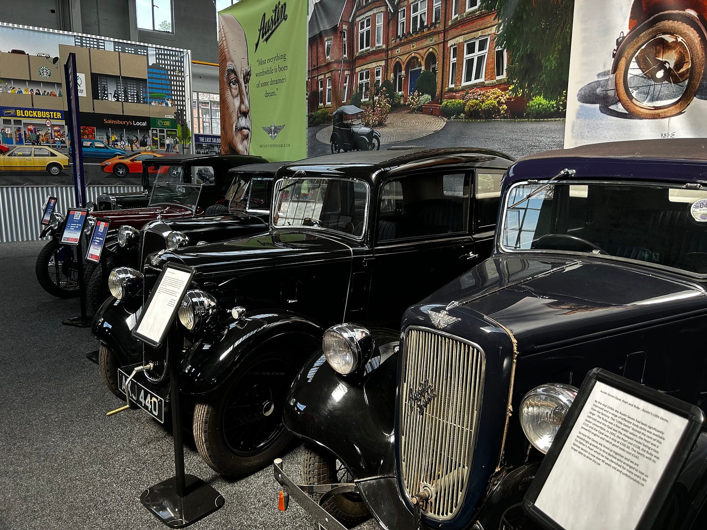 A row of old black Austin cars at the Great British Car Journey. These are located in the main entrance.