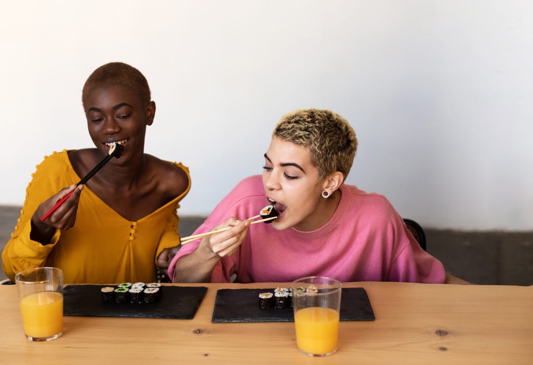 Happy interracial lesbian couple eating sushi