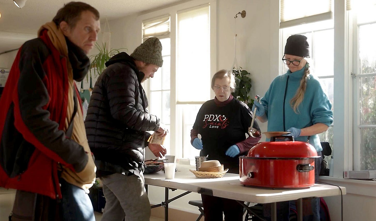 In this screenshot from video, workers at PDX Saints Love Day Center serve a warm meal to visitors.