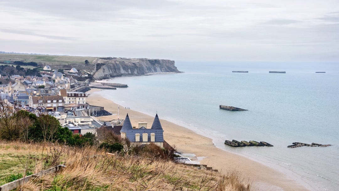 Beachside town, seen from a high point. In the sea are remnants of huge concrete blocks.