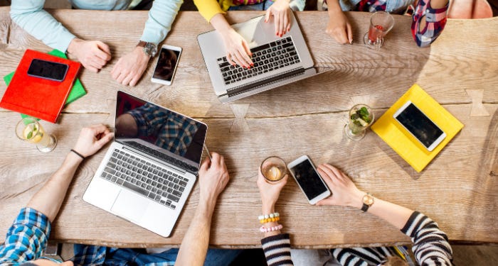 a topdown photo of people around a table with laptops and phones