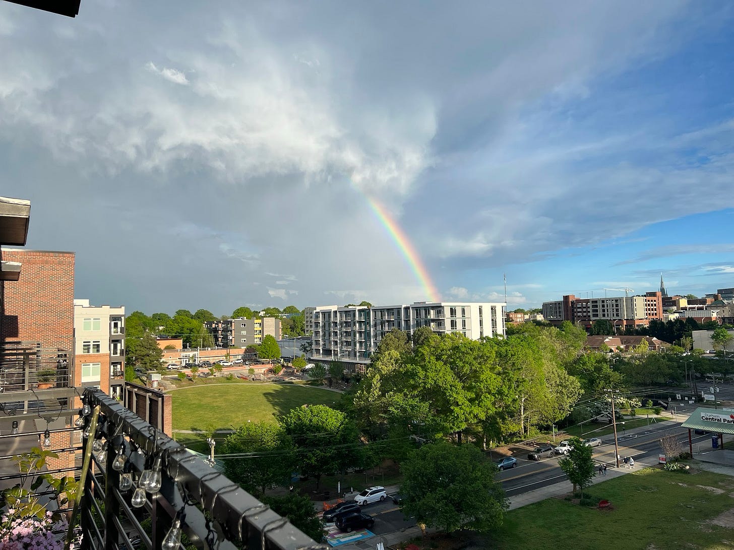 a photo taken from a balcony with a rainbow in the middle of the view