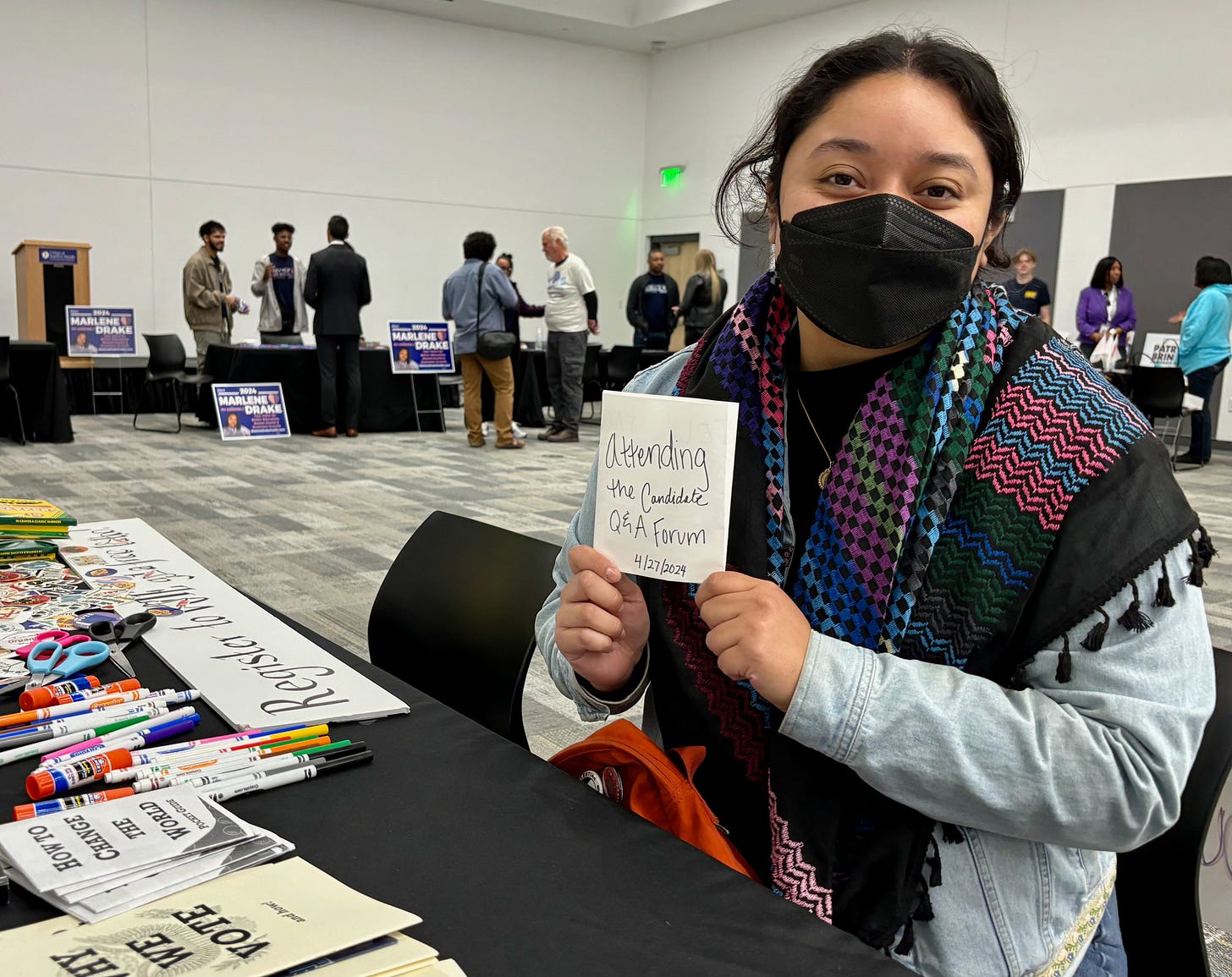 Woman in a black face mask and multicolored scarf holds up a handmade zine Woman in a black face mask and multicolored scarf holds up a handmade zine