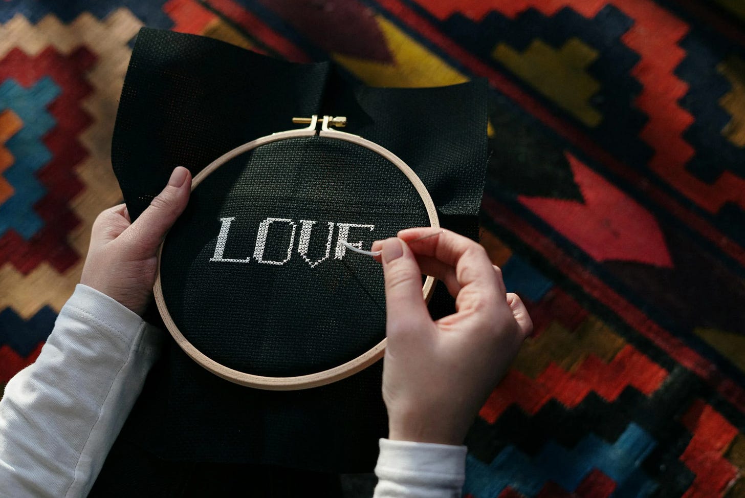 a person writing embrodery with the word LOVE