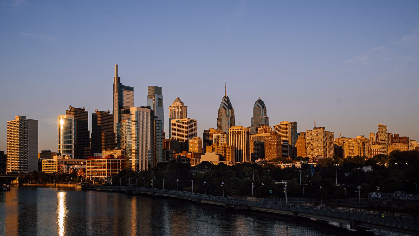 A picture of the Philadelphia skyline against a blue sky at sunrise.