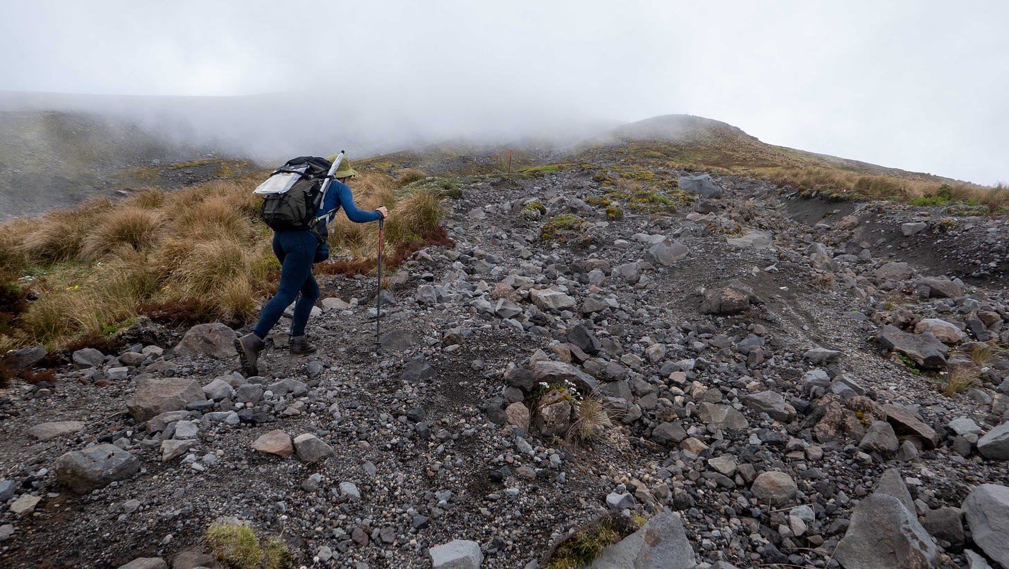 Julia apparently striding up through loose fragments of rock, towards cloud