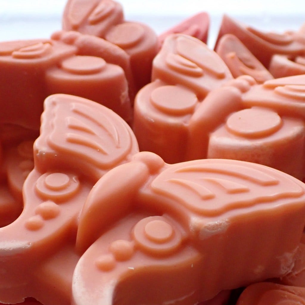 a close up of bright coral butterfly-shaped soap bars