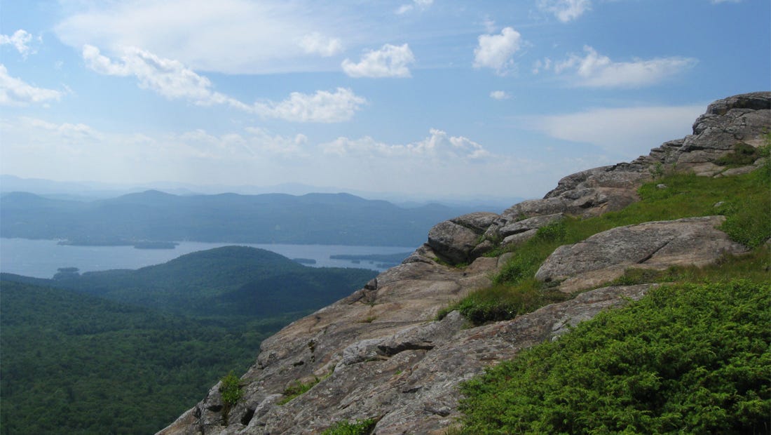 View from a rocky outcropping in the Adirondacks, lake and islands a few miles away, more peaks in the distance perhaps 50.