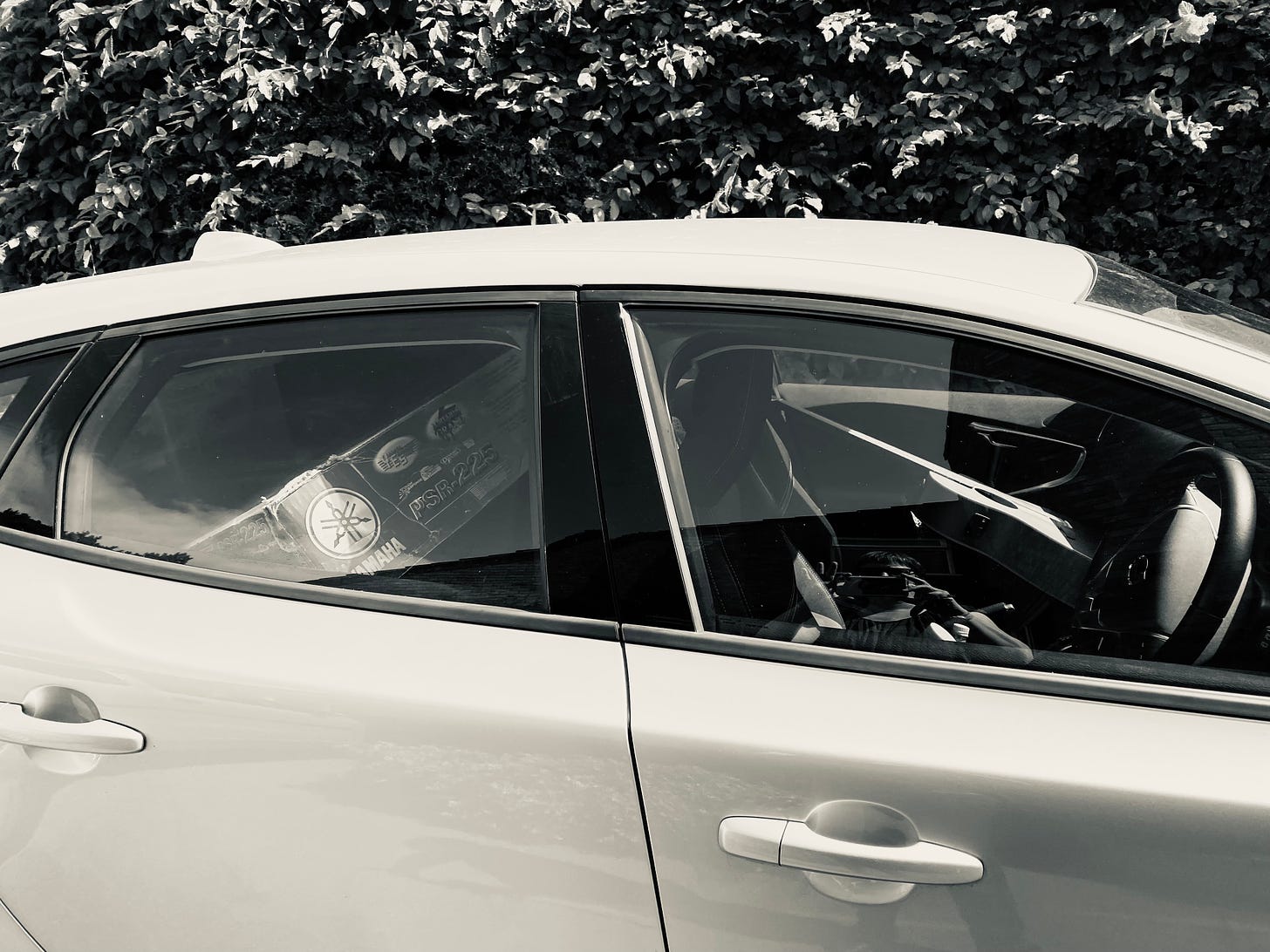 black and white photo of a car, with a few possessions in - just the things they could carry out of the house without 'dad' noticing when they left. A guitar and a box with a keyboard in are visible.