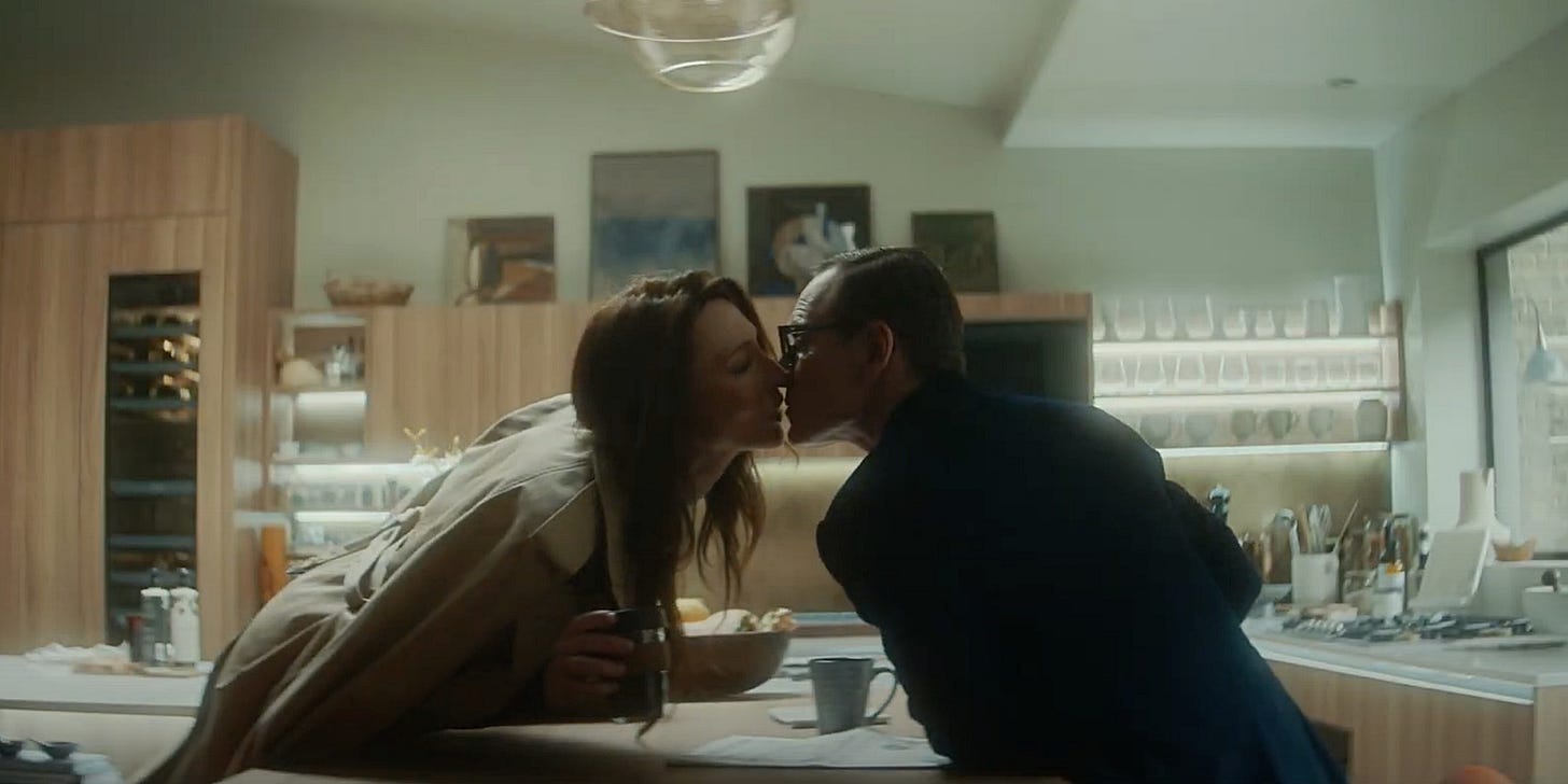 Movie still from Black Bag. A couple lean in for a kiss in their modern kitchen