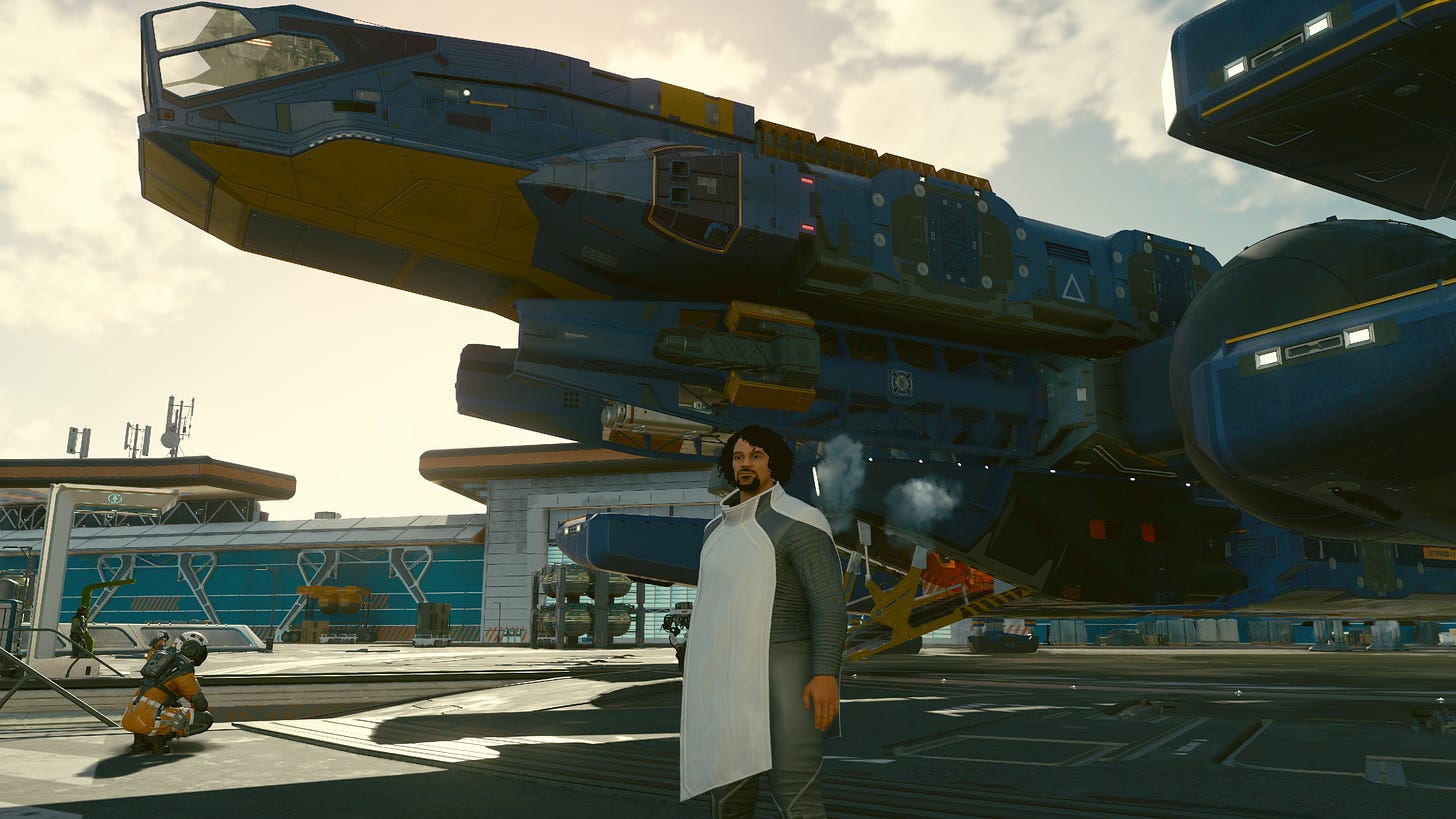 a male character stands in the foreground, black hair and brown complexion with a white poncho and gray clothing underneath. Behind them is a large spaceship.