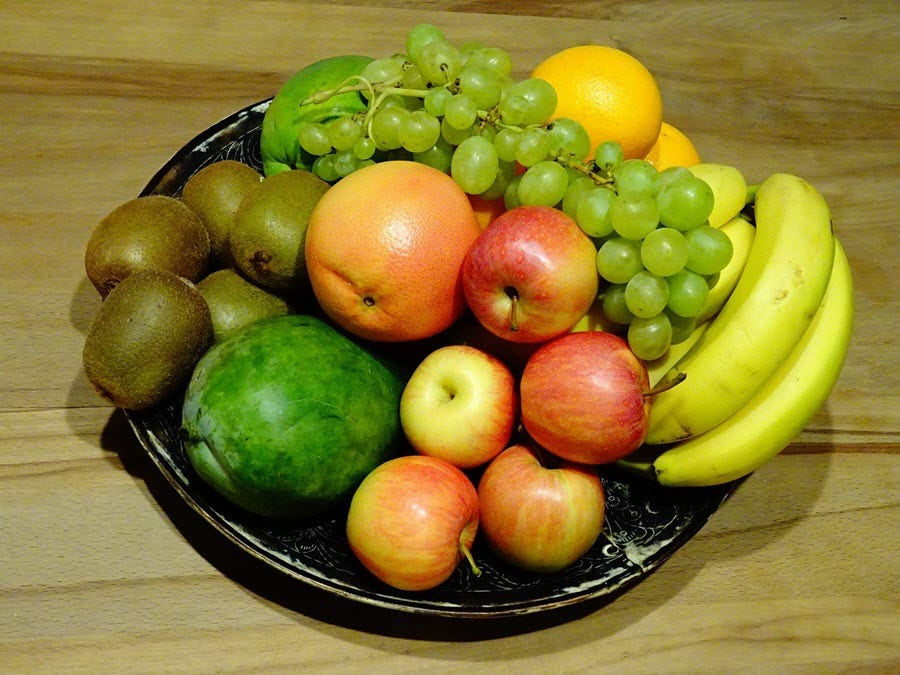 Fruit bowl on table with apple, banana, orange, grape and kiwi fruit