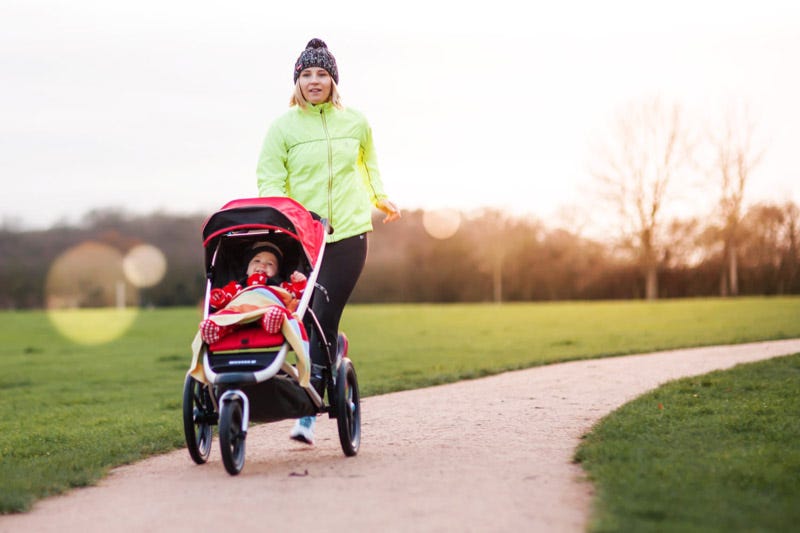 Une femme court avec son enfant dans une poussette