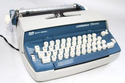 Picture of a blue and white electric typewriter with the Smith Corona logo on the front.