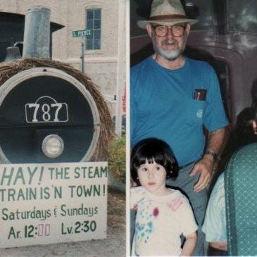 Lyric and their grandfather are on the steam train, next to a sign for the train that says “HAY! The steam train is in town on Saturdays and Sundays!”