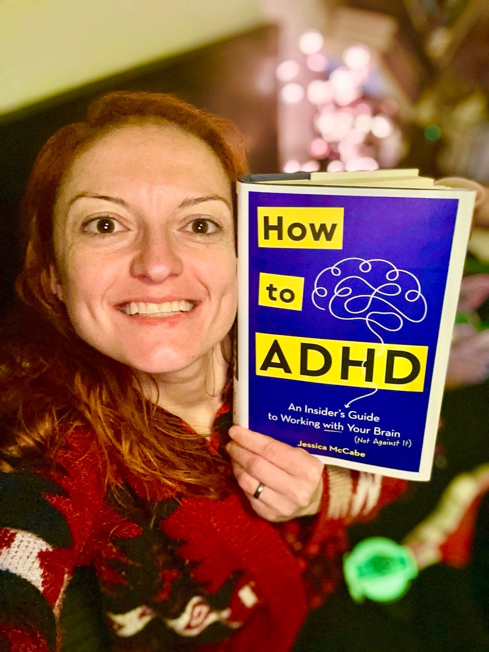 Irina Gonzalez of Raising Gen Alpha holding the book How to ADHD by Jessica McCabe