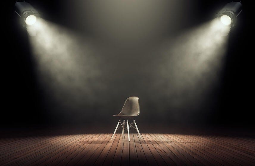 Spotlights illuminate empty stage with chair in dark background ...