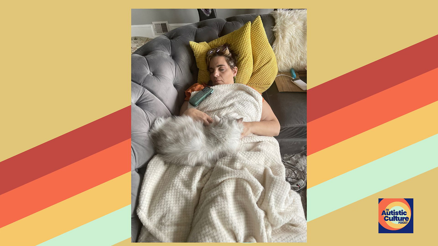 The author demonstrating emotional regulation and burn-out prevention by lying (mid-work-day) on a gray couch, resting under a cream blanket with a fluffy white cat sleeping on their chest. The person is wearing an orange shirt, with yellow cushions behind them and a TV remote on their chest. 