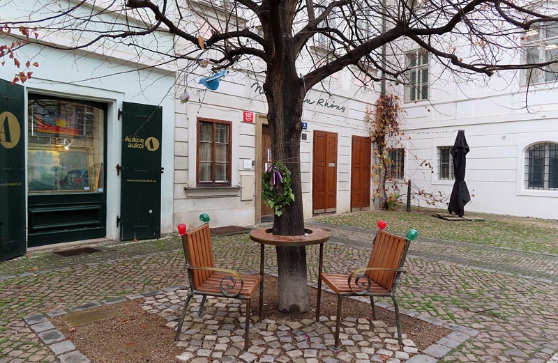 two chairs and a round table built around the trunk of a tree