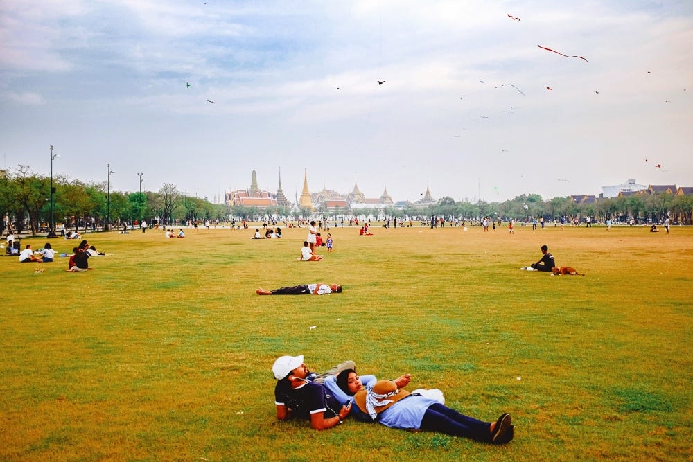 People lying on the grass and flying kites in Sanam Luang Park, Bangkok