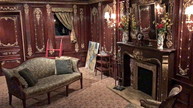Rose's sitting room from Titanic featuring dark wood paneling with gold leaf.