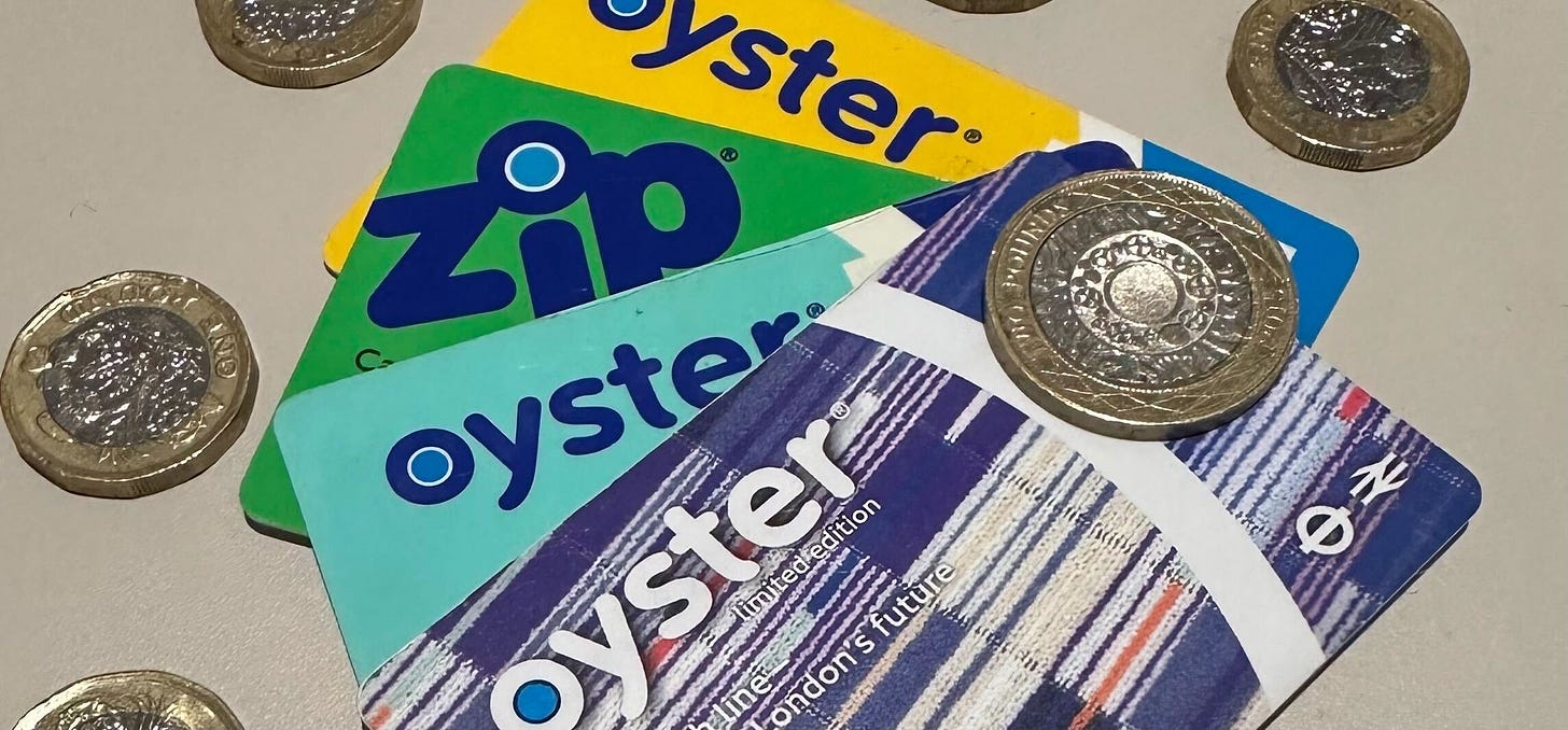 Four Oyster cards stacked with coins laying around them