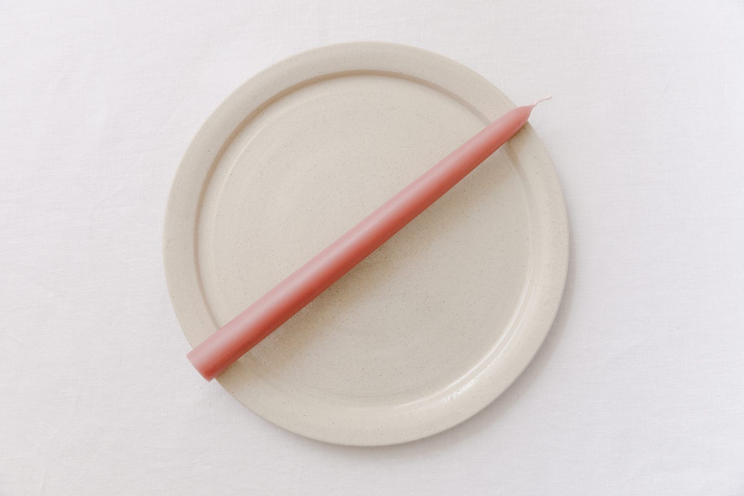a dinner candle placed at an angle on a plate.