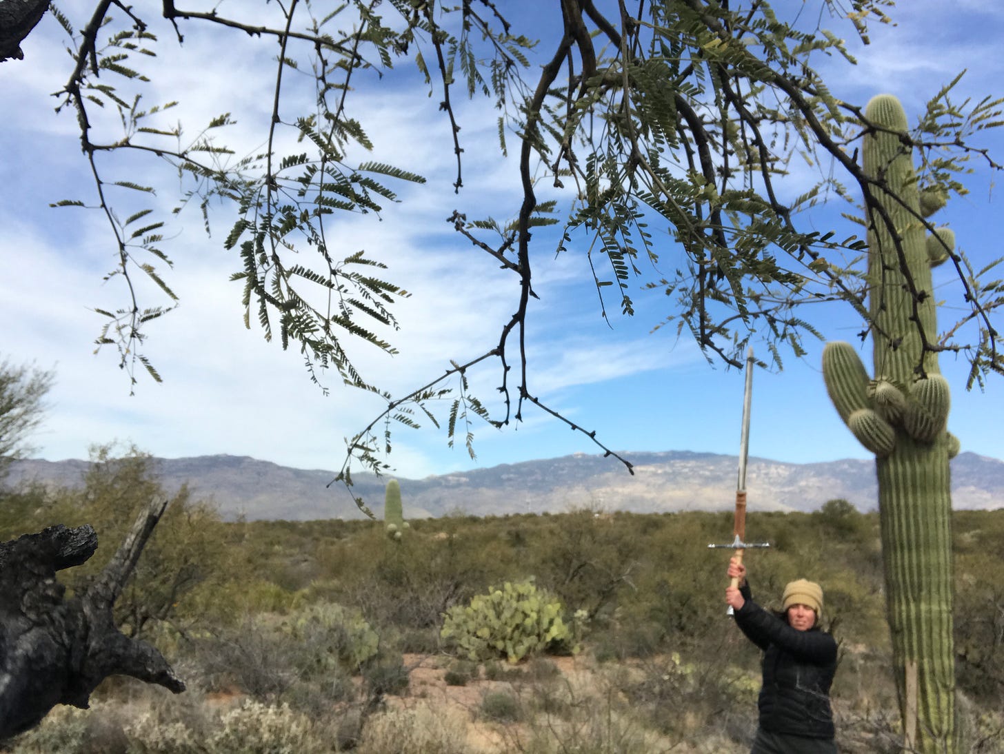 A woman (the author) wielding a sword next to a saguaro